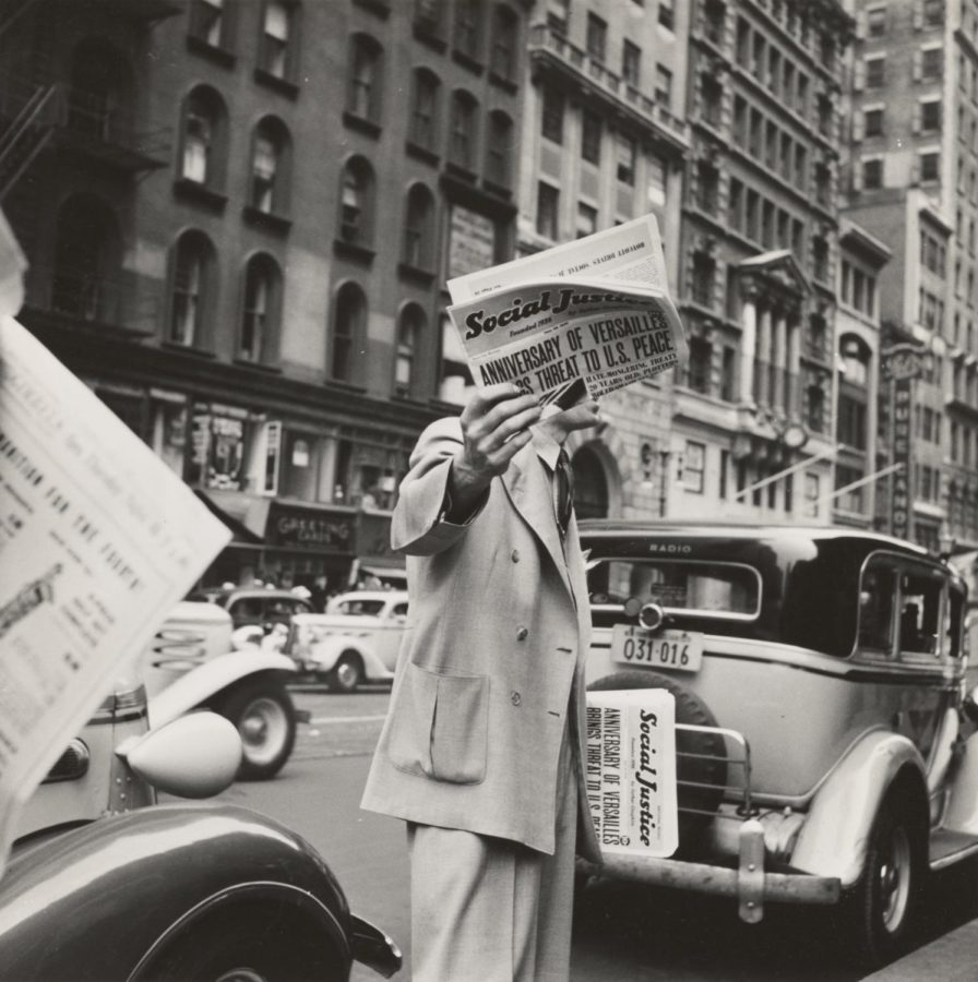 Black and white photo of man holding a newspaper.