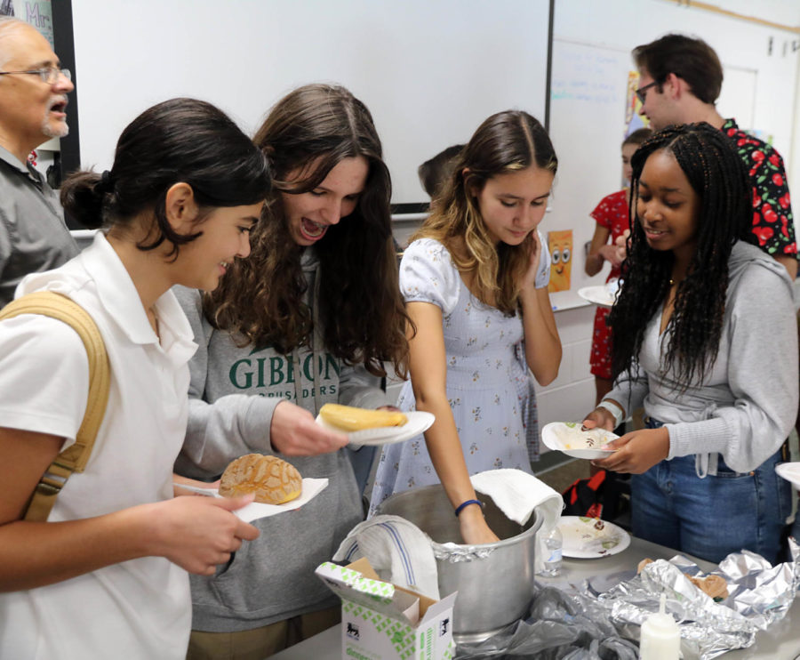 Four students enjoy food from the potluck.